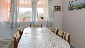 Een eetkamer met een lange tafel, gestreepte stoelen en een tafelkleed met bloemen.