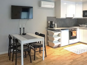 Cocina compacta con comedor, televisor de pantalla plana y horno empotrado.