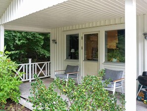 En inglasad veranda med två stolar och en grill.