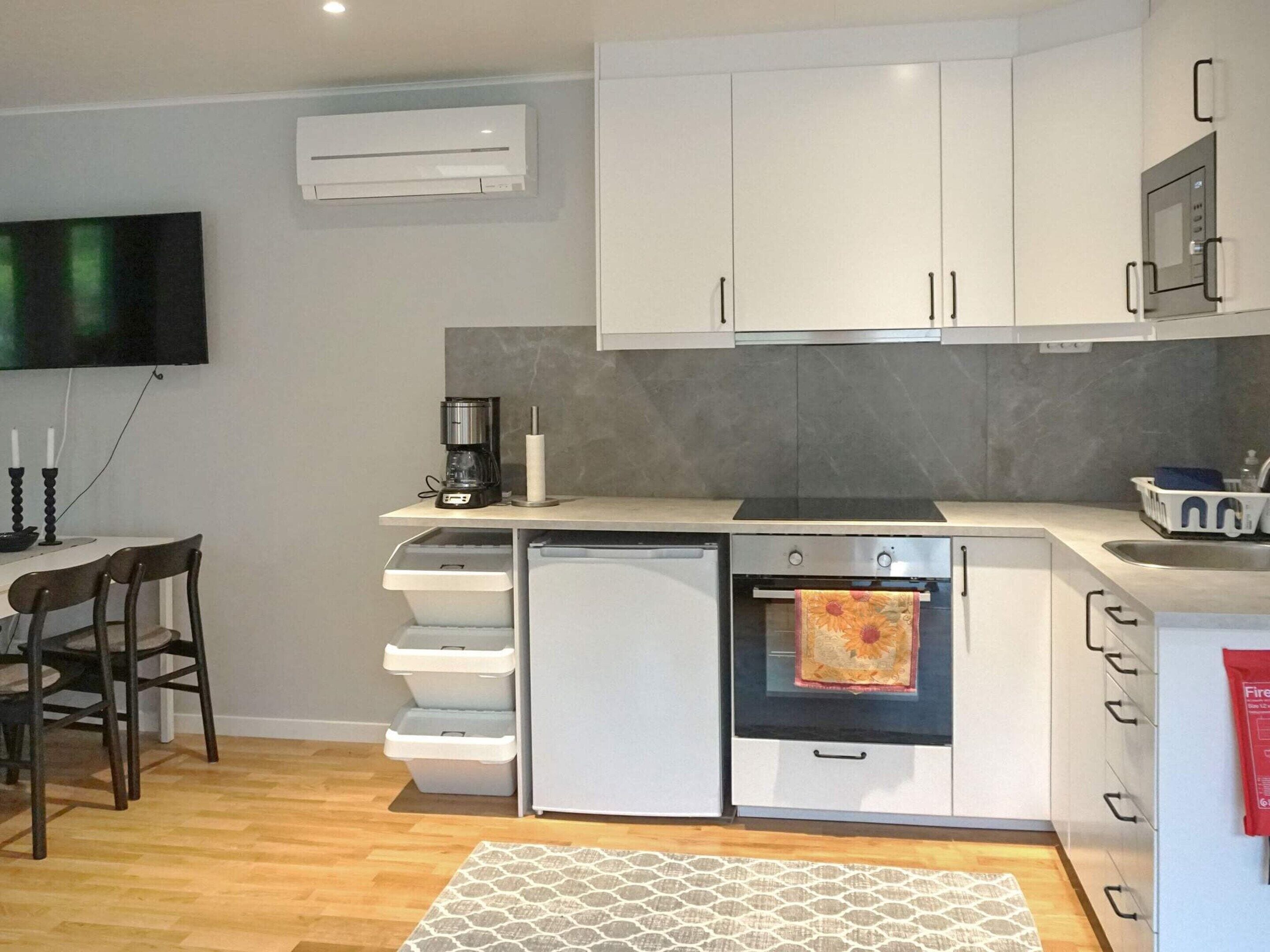 A compact kitchen with white cabinets, a built-in oven, a microwave, and a coffee maker.