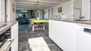 Eine moderne Küche mit weißen Schränken, einem Essbereich mit Tisch und Stühlen sowie einer sichtbaren Kochinsel mit Spüle.
