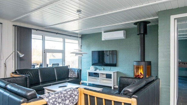 Ein modernes Wohnzimmer mit einer Couch, einem Couchtisch, einem Fernseher und einem Kaminofen.