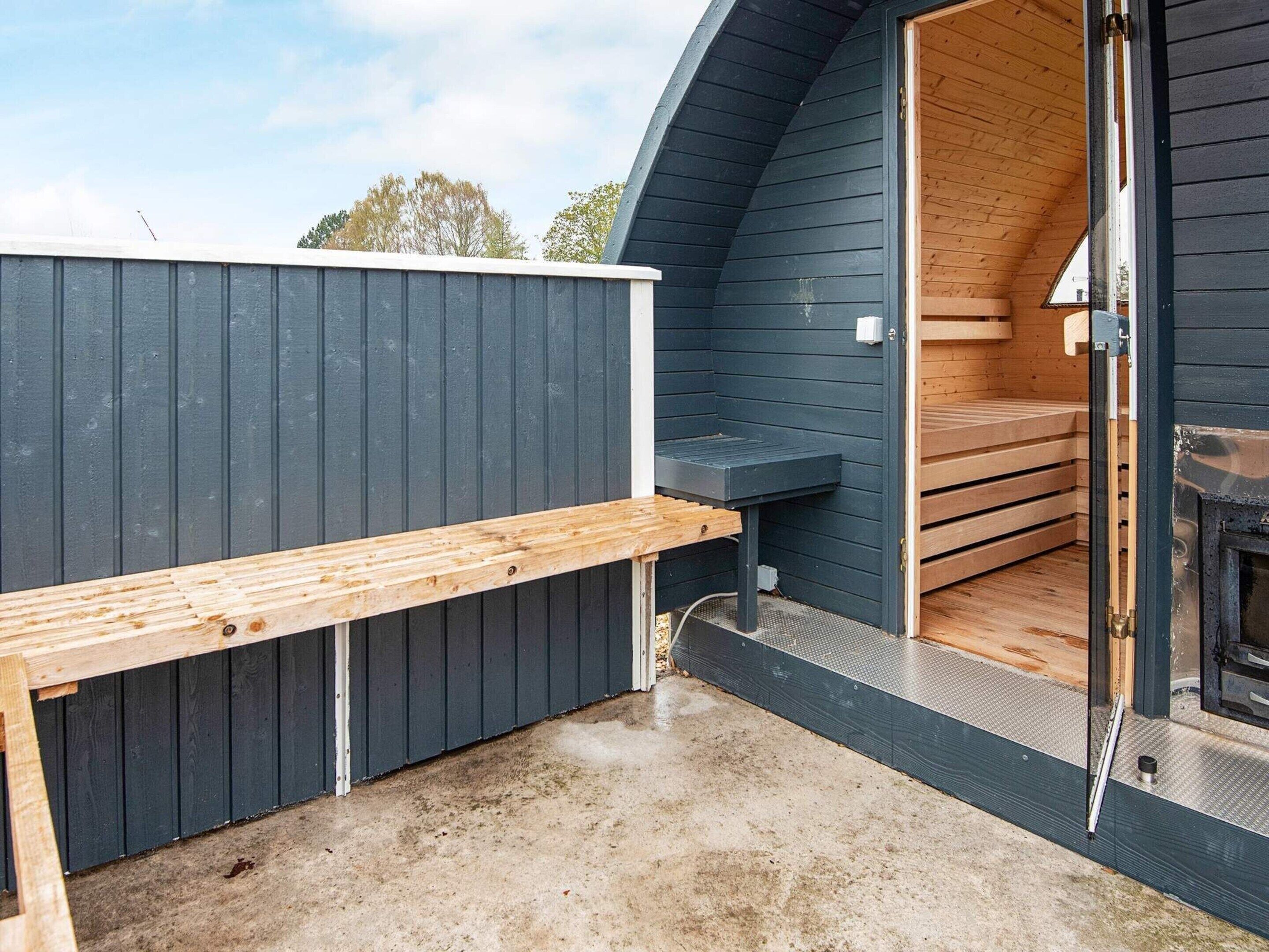 Uma sauna com um banco e outro banco de madeira no exterior.