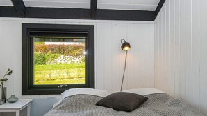 A bedroom with a bed, a nightstand, a lamp, and a window with a view of greenery. - 4 Person Holiday Home in Hejls (Hejls)