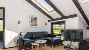 A modern living room with a black leather sofa, a round coffee table, and a flat-screen TV. - 4 Person Holiday Home in Hejls (Hejls)