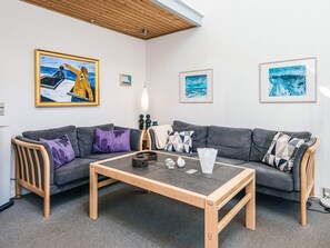 A modern living room with a grey sofa, a wooden coffee table, and artwork on the walls.
