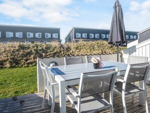A deck with a table and chairs, surrounded by a grassy area and a fence. - 6 Person Holiday Home in Vestervig (Vestervig)