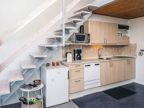 A compact kitchen with a built-in microwave, a coffee maker, and a sink.