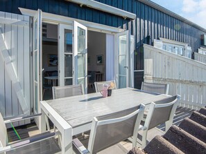 A covered outdoor seating area with a table and chairs, a wooden deck, and a white fence. - 6 Person Holiday Home in Vestervig (Vestervig)