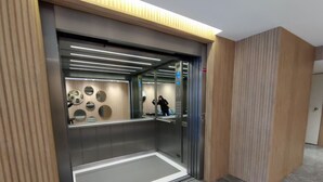 An elevator with a modern design, featuring a metallic interior and a wooden panel on the sides.
