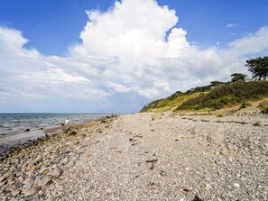 A pebble beach with a clear sky and distant hills. - 8 Person Holiday Home in Gilleleje (Gilleleje)