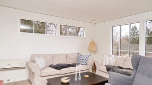 A living room with a beige sofa, a grey armchair, a dark wooden coffee table, and a pink rug. - 8 Person Holiday Home in Gilleleje (Gilleleje)