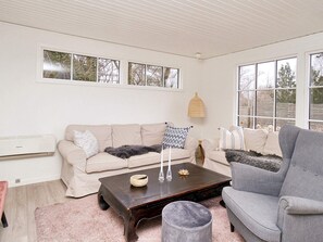 A living room with a beige sofa, a grey armchair, a dark wooden coffee table, and a pink rug. - 8 Person Holiday Home in Gilleleje (Gilleleje)