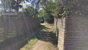 A narrow dirt path flanked by brick walls, leading to a vehicle parked in the distance. - 8 Person Holiday Home in Gilleleje (Gilleleje)