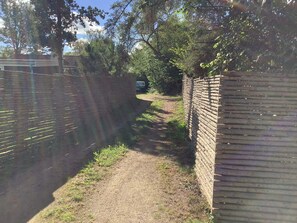A narrow dirt path flanked by brick walls, leading to a vehicle parked in the distance. - 8 Person Holiday Home in Gilleleje (Gilleleje)