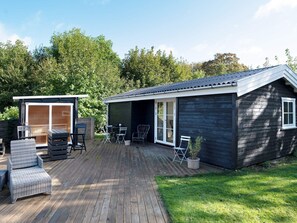 A wooden deck with outdoor furniture, a covered patio, and a small shed.