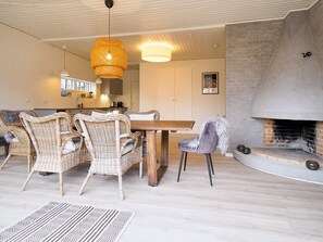 A modern living room with a fireplace, wicker furniture, and a dining area.