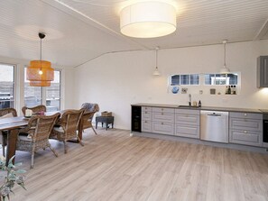 A modern kitchen with a dining area, featuring a large island, white cabinetry, and a hanging light fixture.