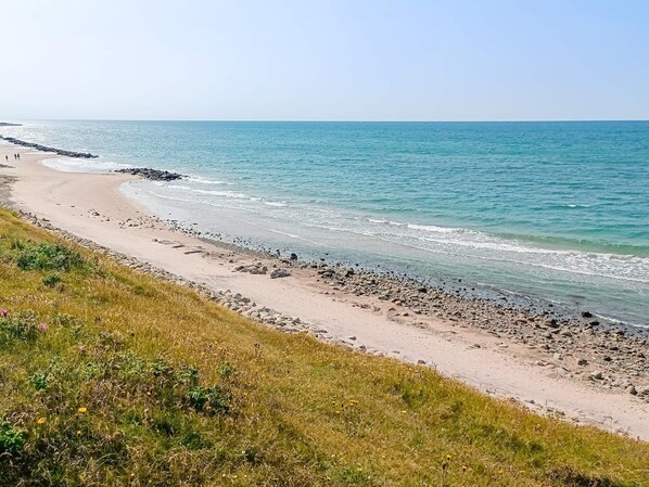 A coastal beach with a rocky shoreline and grassy areas.