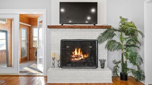 A fireplace with a TV above it, a potted plant, and a view into another room. - Beautiful Bayfront with Sanctuary Private Beach  (Saxis)