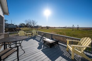 A wooden deck with outdoor furniture, including chairs and a table, overlooking a grassy field. - Beautiful Bayfront with Sanctuary Private Beach  (Saxis)