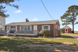 A two-story brick house with a front porch, a small front yard, and a red barn in the background. - Beautiful Bayfront with Sanctuary Private Beach  (Saxis)