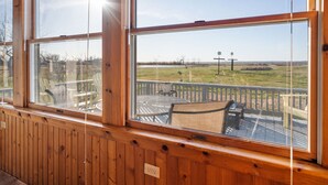 A wooden deck with outdoor furniture and a clear view of a grassy field and distant structures. - Beautiful Bayfront with Sanctuary Private Beach  (Saxis)