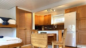 Une cuisine de taille réduite, dotée de meubles en bois, d’un réfrigérateur blanc et d’une table à manger avec des chaises.