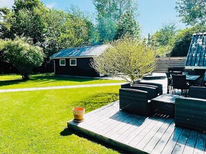 A patio area with outdoor furniture, a small building, and a well-maintained lawn. - 4 Star Holiday Home in Gilleleje (Gilleleje)