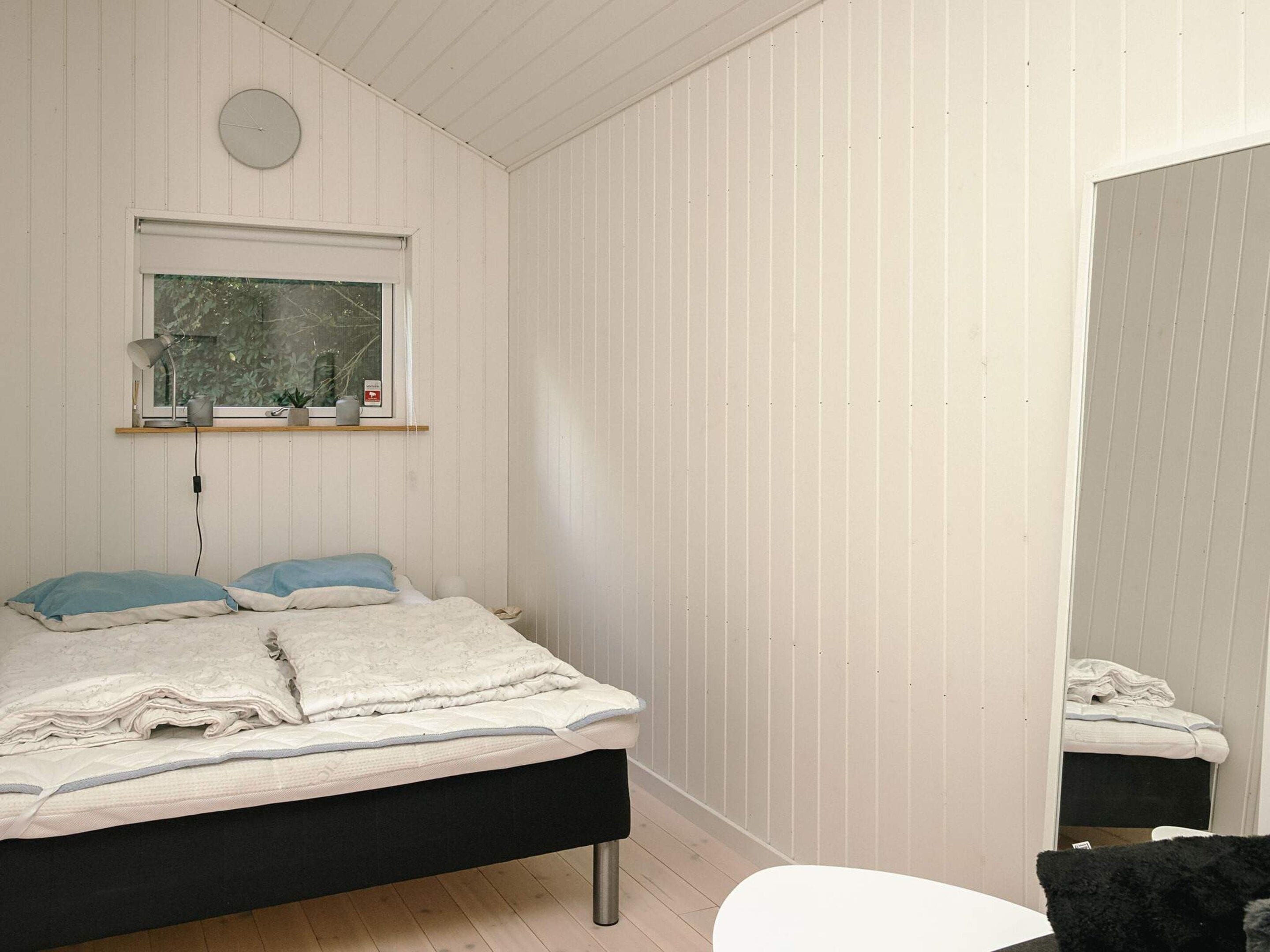 Une chambre à coucher avec un lit, une table de chevet, une fenêtre donnant sur un beau paysage et un miroir.