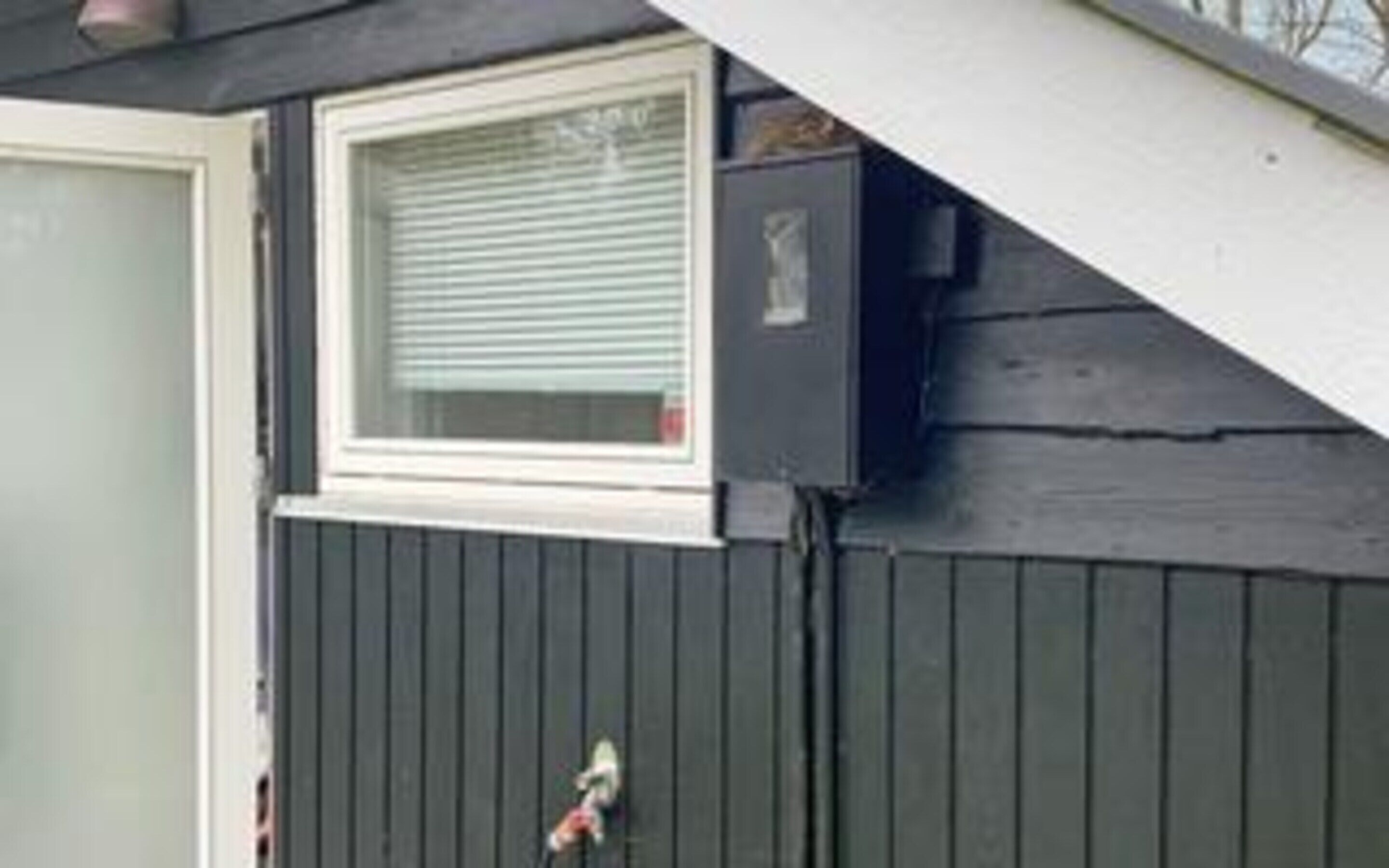 A building with a window, a door, and a small outdoor area with a hose.