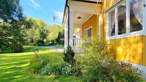 A yellow building with a balcony, surrounded by greenery and a clear sky. - 13 Person Holiday Home in Billingfors (Billingsfors)