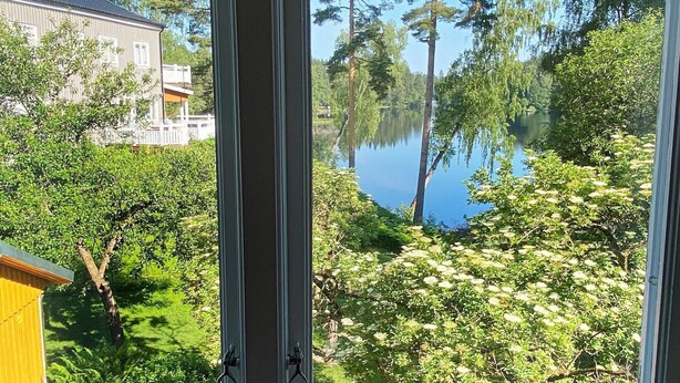 A view through a window of a lake surrounded by trees and a building. - 13 Person Holiday Home in Billingfors (Billingsfors)