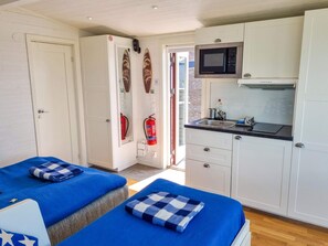 A room with two beds, a kitchenette with a microwave, and a door leading to another room.