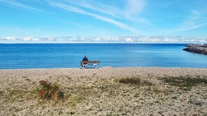 A bench on a pebbled beach with a clear view of the ocean and distant land. - 3 Person Holiday Home in Lottorp (Löttorp)