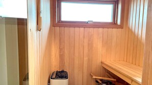 A sauna room with wooden walls, a window, a heater, and a shelf with a pot. - 3 Person Holiday Home in Lottorp (Löttorp)
