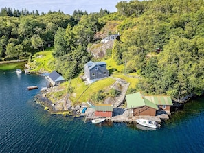 A coastal property with a main house, a smaller cabin, and a dock with boats. - 8 Person Holiday Home in Sveio-by Traum (Sveio)