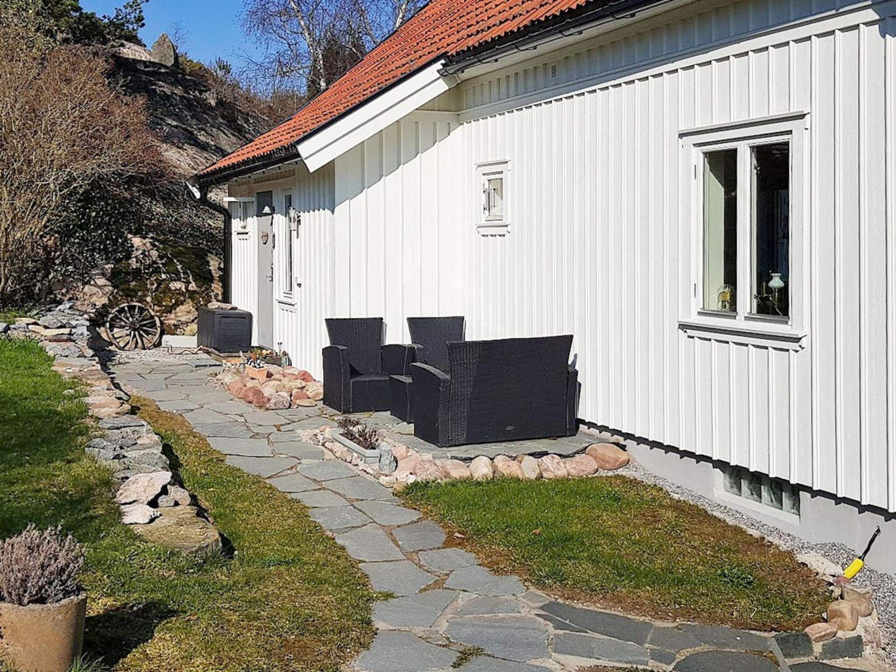 A white building with a stone pathway leading to a seating area with two chairs.