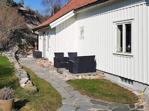Un bâtiment blanc avec un chemin de pierre menant à un espace aménagé avec deux chaises.