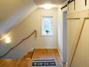 A hallway with wooden flooring, a window with a plant, and a door with a black and white striped doormat. - 4 Star Holiday Home in Hoviksnas (Höviksnäs)