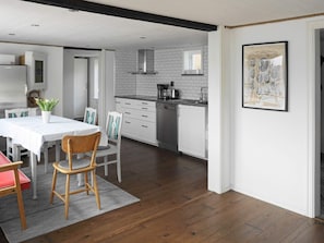 A modern kitchen with white cabinets, a stainless steel range hood, and a coffee maker on the counter.