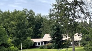 A house with a sloped roof, surrounded by dense trees and a body of water. - 8 Person Holiday Home in Skyllberg-by Traum (Skyllberg)