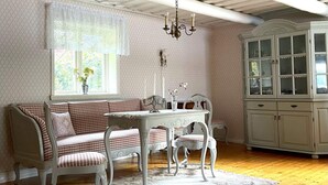 A room with a white checkered bench, a white table with chairs, a chandelier, and a white cabinet with glass doors. - 8 Person Holiday Home in Skyllberg-by Traum (Skyllberg)