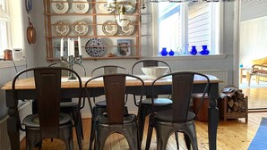 A dining area with a wooden table and metal chairs, a wall-mounted plate rack, and a window with blue vases. - 8 Person Holiday Home in Skyllberg-by Traum (Skyllberg)
