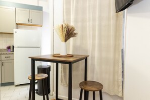 Enjoy cooking in this kitchen with a refrigerator, table, and stools.