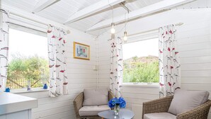 A cozy room with two wicker chairs, a small round table with a vase of flowers, and a window with patterned curtains. - 6 Person Holiday Home in Bremnes-by Traum (Bomlo)