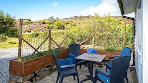 An outdoor patio with a table and four chairs, a wooden bench, and a view of a hilly landscape. - 6 Person Holiday Home in Bremnes-by Traum (Bomlo)