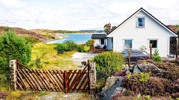 A coastal house with a wooden gate, a car parked in front, and a view of the sea. - 6 Person Holiday Home in Bremnes-by Traum (Bomlo)
