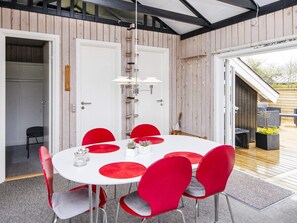 Un coin repas avec une table blanche, des chaises rouges et un luminaire suspendu.