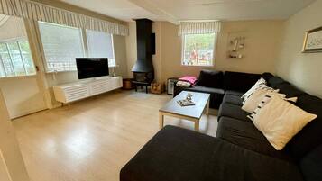 A living room with a black sofa, a coffee table, a fireplace, and a television on a white stand.